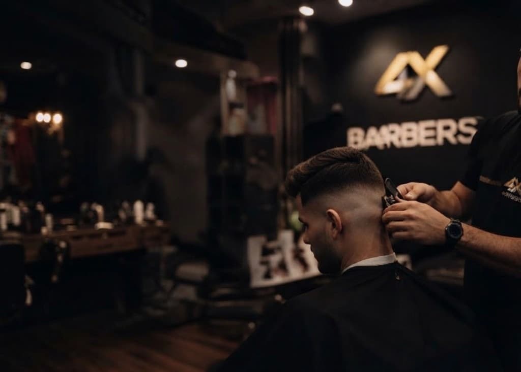 A barber finishing a fade at 4X Barbers